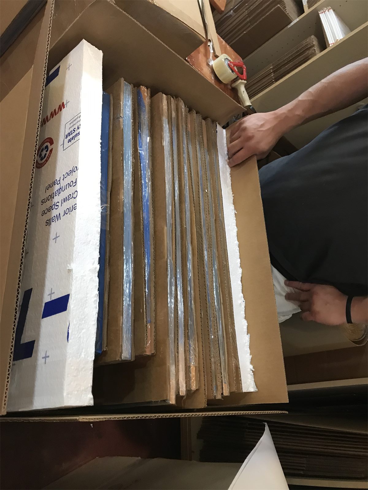 Stack of flat artwork and framed pieces separated and protected for shipment