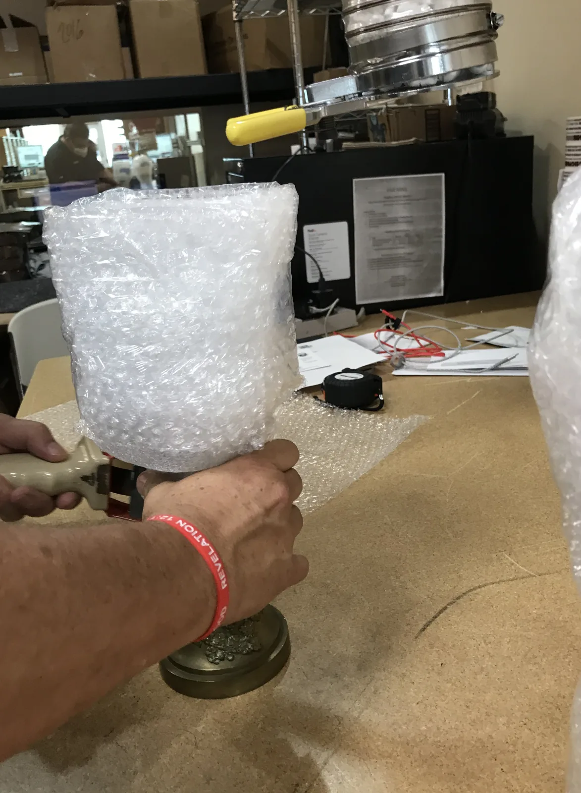 Hands applying bubble protection to a fragile decorative lamp