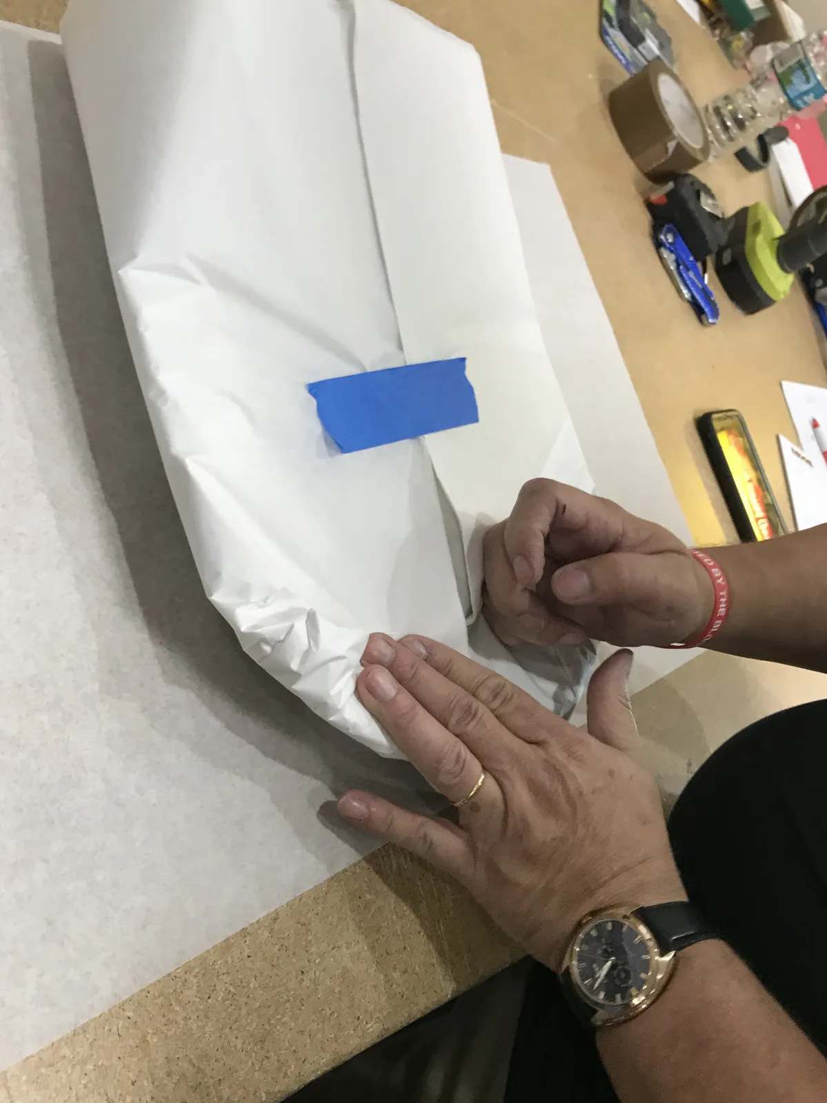 Hands folding protective material around a fragile item